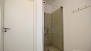 Un baño con ducha de vidrio, inodoro y lavamanos blanco.