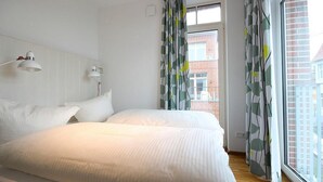 Un dormitorio con una cama grande, dos lámparas de noche y un ventanal con cortinas.