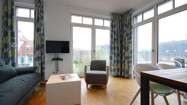 Una sala de estar moderna con un sofá, una mesa de centro, un televisor y una mesa de comedor con sillas.