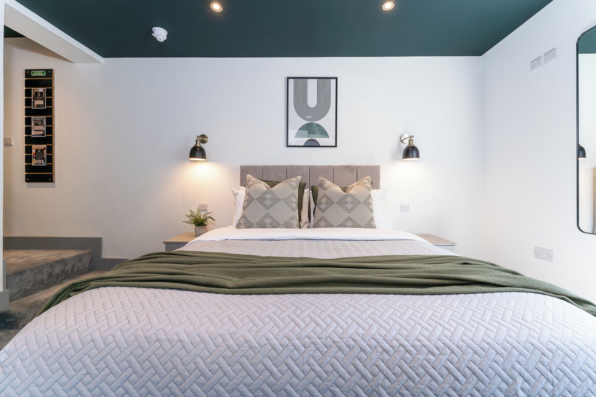 Una camera da letto moderna con un letto, una testiera, comodini e un’opera d’arte appesa al muro.