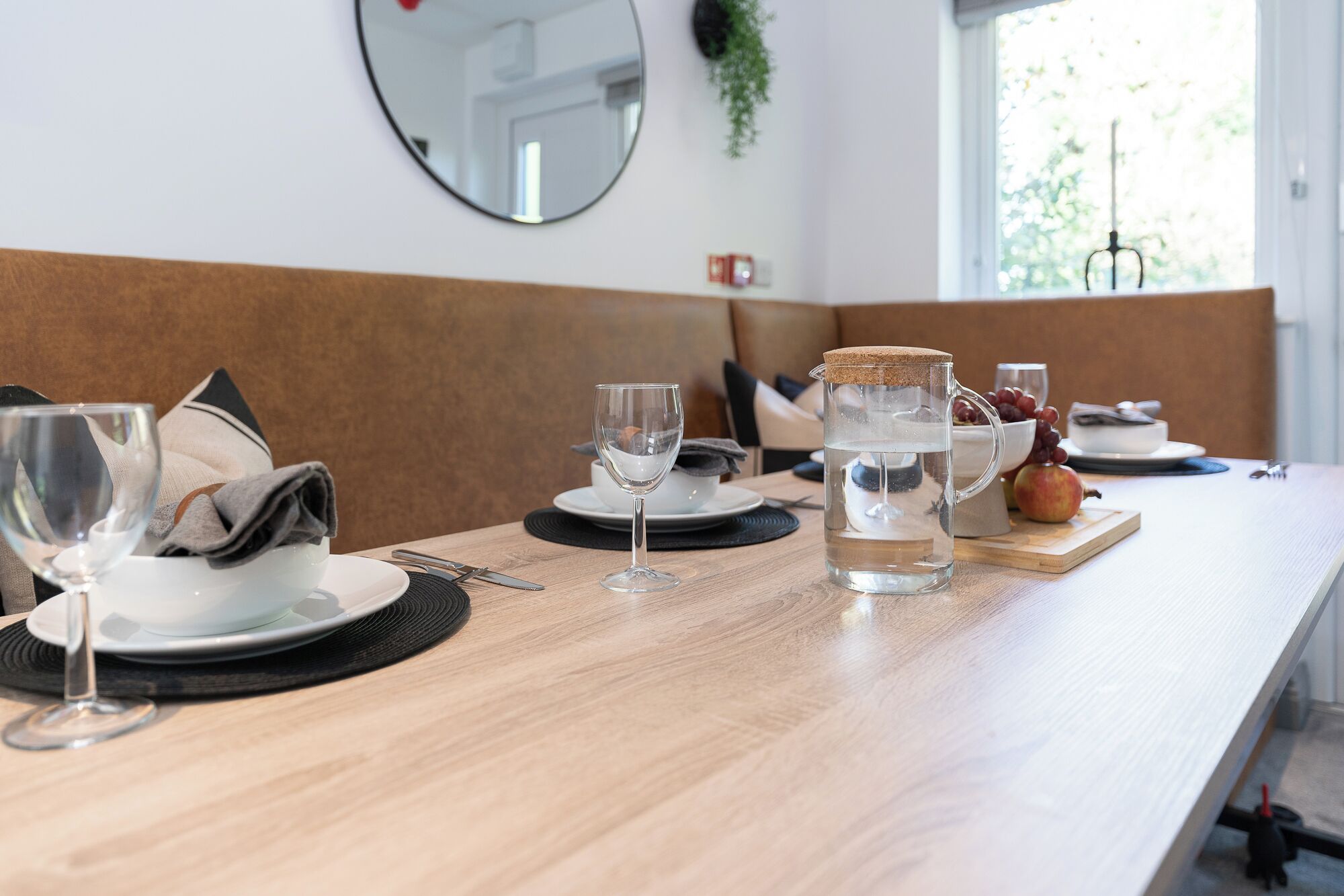 A dining table set with plates, glasses, and a pitcher of water.