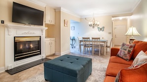 A living room with a fireplace, a television, a dining area, and a sofa. - Dolly Dreams - Fireplace, Minutes to Dollywood! (Pigeon Forge)