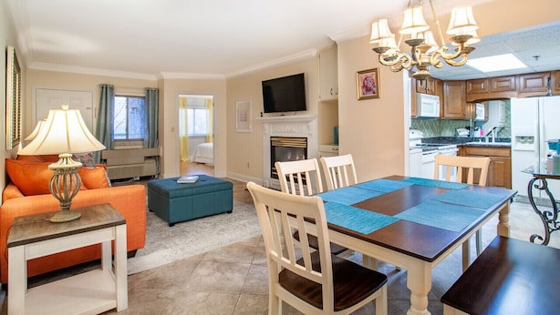 A living room with a fireplace, a dining table, and a kitchen area with cabinets and a microwave. - Dolly Dreams - Fireplace, Minutes to Dollywood! (Pigeon Forge)