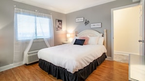 A bedroom with a bed, a nightstand, a wall clock, and a window with blinds. - Dolly Dreams - Fireplace, Minutes to Dollywood! (Pigeon Forge)