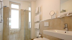 A modern bathroom with a glass shower enclosure, a white sink, and a mirror. - Tolles Ferienapartment mit Großem, Sonnigen Südbalkon - nur 100 m zum Strand! (Nordseeheilbad Wangerooge)