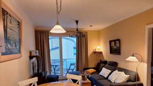 Een gezellige woonkamer met een houten eettafel, een bank en een balkon met uitzicht.