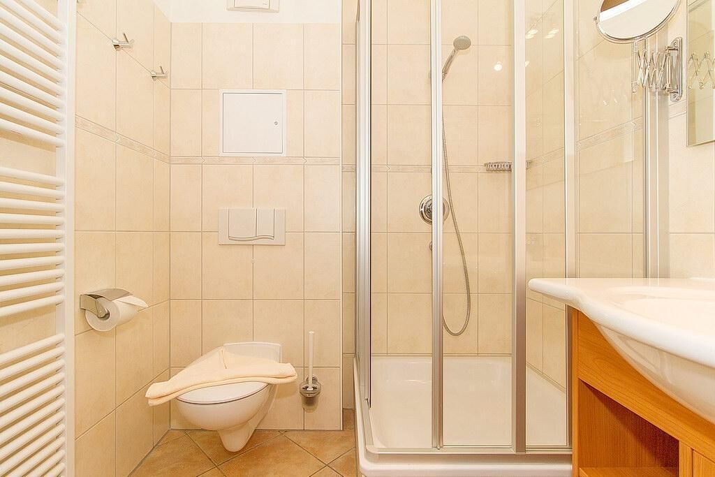 A bathroom with a toilet, a shower enclosure, and a sink with a mirror.