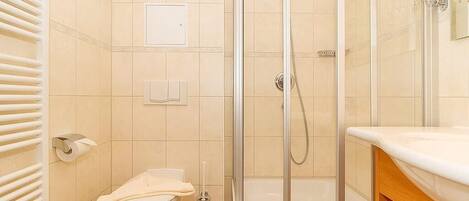 Un baño con inodoro, cabina de ducha y lavabo con espejo.