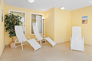 Ein Zimmer mit zwei weißen Lounge-Sesseln, einem Blumentopf und einem Gemälde an der Wand.