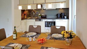 Una cocina moderna con armarios blancos, una mesa de comedor para dos personas y una cafetera.