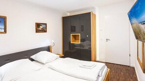 Ein Hotelzimmer mit einem großen Bett, einem Kleiderschrank, einem Fernseher und Bildern an der Wand.