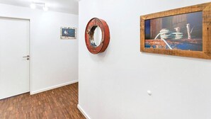 Ein Flur mit weißen Wänden, Holzboden, einem runden Spiegel und einem gerahmten Gemälde.