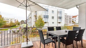 Ein Balkon mit Tisch und Stühlen, ein Fahrrad und Blick auf Gebäude.
