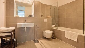 A modern bathroom with a glass shower enclosure, a white sink, and a bathtub.