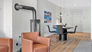 Una cocina moderna con una isla central, un comedor con una mesa redonda y sillas, y una estufa visible con campana extractora.