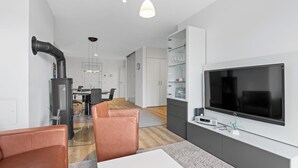 Una sala moderna con televisión, sillones de cuero, comedor y cocina.