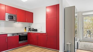 Una cocina moderna con armarios rojos, electrodomésticos de acero inoxidable y piso de madera.