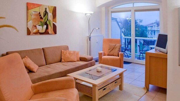 A living room with a sofa, armchairs, a coffee table, and a painting on the wall.