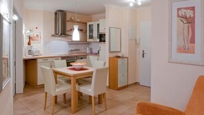 A compact kitchen with a dining area, featuring a table with chairs, a small refrigerator, and a microwave.