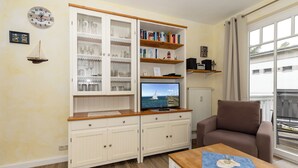 A living room with a TV, wooden cabinet, and a brown armchair.