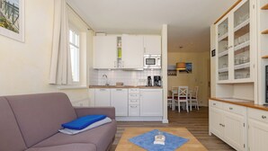 A compact living space with a kitchenette, a sofa, a coffee table, and a dining area.