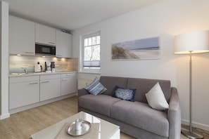 Una sala de estar moderna con un sofá gris, una mesita de centro y una lámpara de pie.
