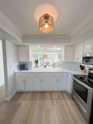 Een moderne keuken met witte kasten, een centraal eiland en een inbouwoven.