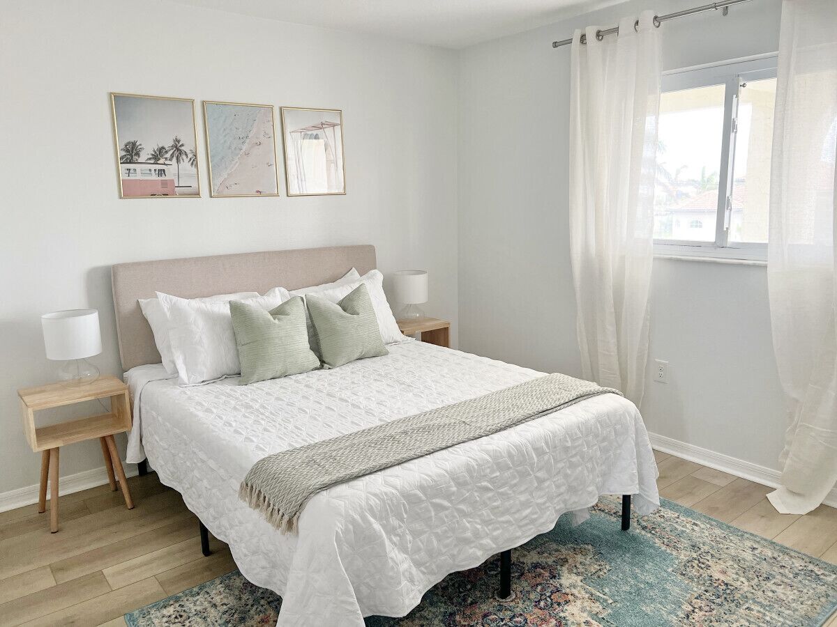 A neatly arranged bedroom with a bed, bedside tables, and artwork on the wall.
