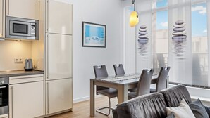 A modern kitchen with a built-in microwave, a kettle, and a dining area with a table and chairs.