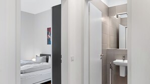 A modern bedroom with a bed, a bedside lamp, and a poster on the wall.