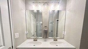 Une salle de bain avec deux lavabos, un grand miroir et un porte-serviettes.