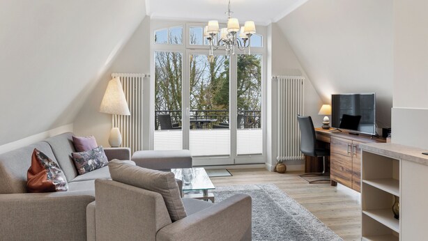 A modern loft bedroom with a large window, a desk, a television, and a sofa.