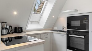A modern kitchen with a skylight, built-in appliances, and a clean design.