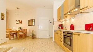Una cocina moderna con armarios de madera, horno empotrado y comedor con mesa y sillas.