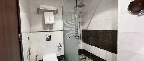 A modern bathroom with a glass shower enclosure, a toilet, a bidet, and a towel rack.