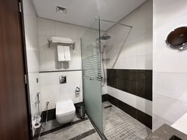 Un baño moderno con cabina de ducha de vidrio, inodoro, bidé y perchero para toallas.