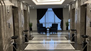 A modern lobby with marble floors, two sofas, and a large window with curtains. - Zaha Taiba Hotel (Madinah)