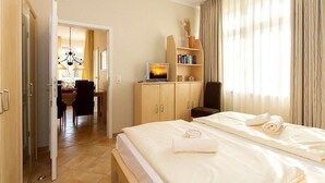 Una habitación de hotel con cama, escritorio, silla, estantería y televisión.
