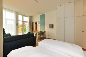Una habitación de hotel moderna con una cama grande, un sofá, un comedor y un armario.