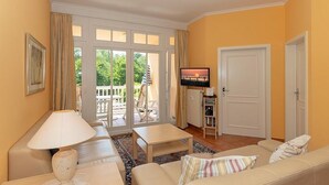 Ein Wohnzimmer mit einer Couch, einem Tisch, einem Fernseher und einer Tür.