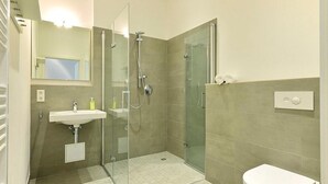 A modern bathroom with a glass-enclosed shower, a sink, and a toilet.