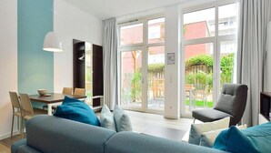 A modern living room with a sofa, armchairs, a dining table, and a TV.