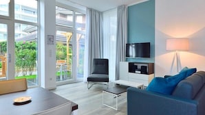 A modern living room with a sofa, a chair, a TV, and a dining table.