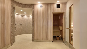 A modern spa area with a curved shower, wooden panel walls, and a wooden sauna.