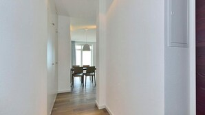 A narrow hallway with wooden flooring and white walls.