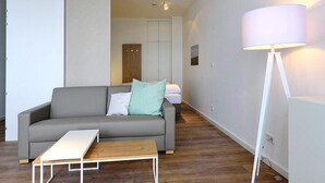 Una sala moderna con un sofá gris, una mesa de centro de madera y una lámpara de pie.