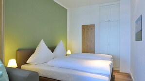 Habitación de hotel con una cama, dos mesitas de noche, un armario y un panel de madera en la pared.