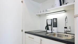 Una cocina moderna con encimera negra, pileta de acero inoxidable y muebles blancos.