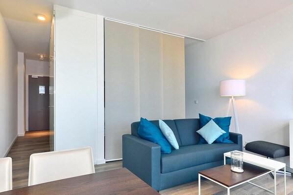 Un salon moderne avec un canapé, une table basse et une lampe.