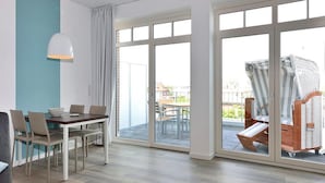 Una habitación moderna con una mesa y sillas de comedor, puertas de vidrio correderas que dan a un patio al aire libre con una mesa y sillas.